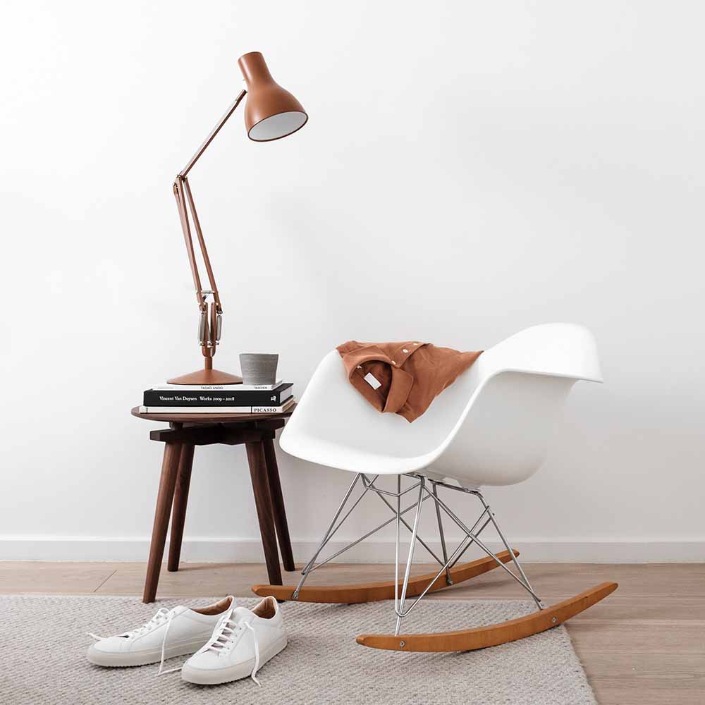 Lampe de bureau Anglepoise Type 75 couleur terre sur une table de chevet et fauteuil a bascule