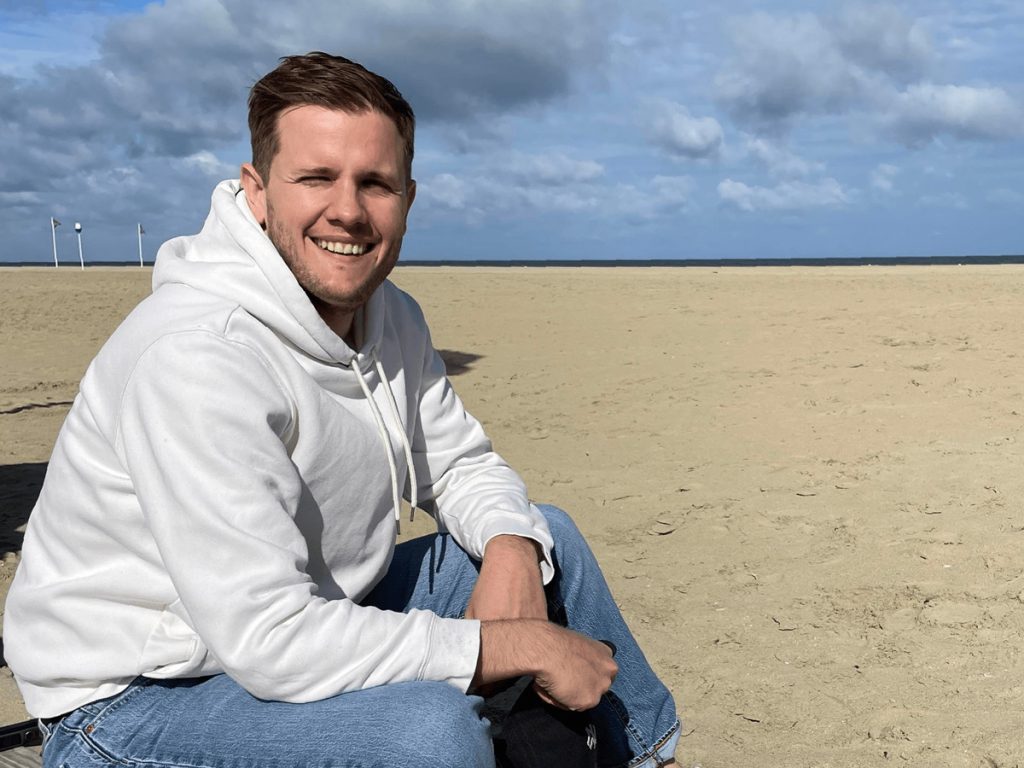 photo de profile de guilaume couet assis sur le sable a la plage